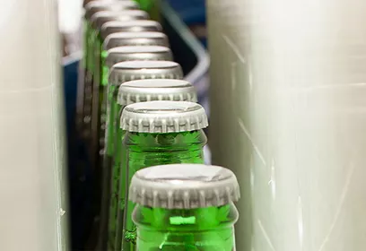 Nahaufnahme von grünen Flaschenhälsen mit Kronkorken in einer Reihe