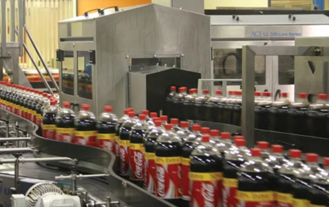 Viele gefüllt Plastikflaschen der Marke CocaCola auf einem Fließband in einer Flaschentrocknung