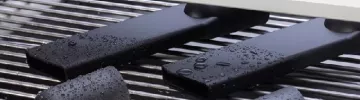 Nasse, schwarze Kunststoffwerkstücke auf einem Gitter