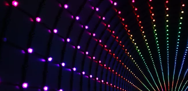 Bunte LED Bahnen, die einen tunnelartigen Gang beleuchten.