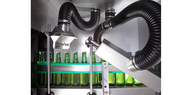 grüne Glasflaschen auf einem Fließband in einer Trocknung, die unter Düsen hindurchfahren